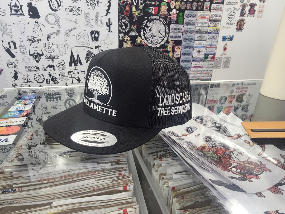 A black branded cap with the white oak mark on the front sitting on a shop counter